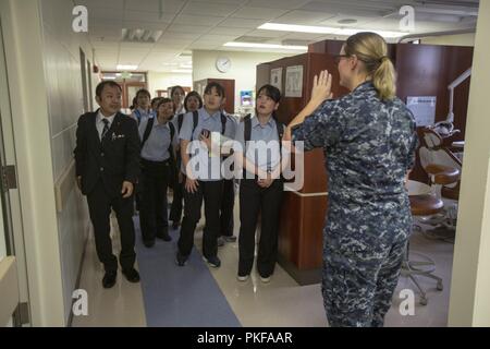 Lt. Betania D. Brooks dirige gli studenti dall'Okinawa igiene dentale scuola durante un tour del ramo Dental Clinic Evans, U.S. Marina Centro dentale, su Camp Foster, Okinawa, in Giappone, il 10 agosto 2018. Igiene dentale gli studenti hanno visitato la clinica di parlare con esperti dentale, consultare le strutture e per saperne di più sul settore dentale. Gli studenti sono attualmente sul loro secondo anno di un corso triennale. Brooks, nativo di Littleton, New Hampshire, è un dentista con 3° Battaglione dentale, 3° Marine Logistics Group. Foto Stock