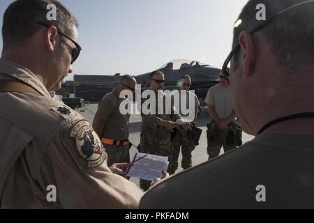 Avieri dal 455th Air Expeditionary Wing (AEW) raccogliere intorno a recitare una preghiera sulla linea di volo a Bagram Airfield, Afghanistan, 10 agosto 2018. La preghiera è stata scritta per l'aeromobile e l'aviatori che operano e mantenerli. L'evento è stato ospitato dal 455th AEW Cappellani Corps che sono incaricati di fornire cura pastorale ministero e counseling a quelle di fede e di quelle di nessuna fede mentre assegnato alla 455th AEW. Foto Stock