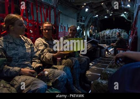 Stati Uniti Air Force Tech. Sgt. Kendell Nielsen, un bioenvironmental engineering tecnico assegnato all'173rd Fighter Wing, passa una confezione di tappi per le orecchie per Senior Airman Laura venditori, un medico tecnico assegnato all'193rd Special Operations Wing, prima del trasporto a bordo di una C-130 Hercules all'Aeroporto di Kahului in Maui, Hi, il 10 agosto 2018. Tropic Care Maui County 2018 è una joint-servizio, "hands-on" disponibilità missione di formazione offrendo nessun costo di personale medico, dentistico e vision servizi alle persone in sei posizioni in tutta Maui Molokai e Lanai da Agosto 11-19. Foto Stock
