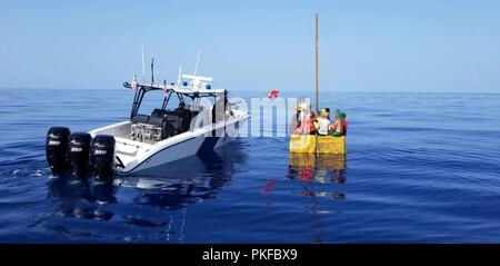 Una delle dogane e della protezione delle frontiere agent lanci un giubbotto salvagente oltre ai cubani emigranti su una nave rustica nei pressi di Maratona, Florida, il 10 agosto 2018. La guardia costiera e delle dogane e della protezione delle frontiere ha lavorato insieme ad interdire 17 cubani illegali e il loro rimpatrio torna a Bahia de Cabañas, Cuba. (Coast Guard foto) Foto Stock