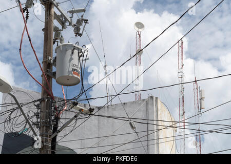 Via i cavi elettrici su un palo con antenne satellitari e antenne radio Foto Stock