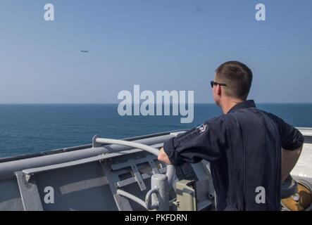 Oceano Pacifico (Agosto 12, 2018) - Lt. Brent Howell, assegnato a Whidbey Island-class dock landing ship USS Rushmore (LSD 47) osserva un P-8A Poseidon volare da durante la collaborazione e la prontezza a galla la formazione (Carati) 2018. CARAT Indonesia, nella sua ventiquattresima iterazione, è progettato per migliorare la condivisione di informazioni e il coordinamento, creare reciproca capacità di combattimento e il sostegno a lungo termine la cooperazione regionale di abilitazione partner di entrambe le forze armate per operare efficacemente insieme come un sistema unificato di forza marittima. Foto Stock