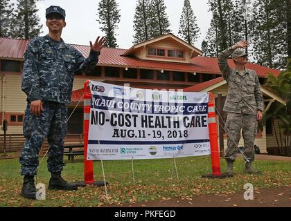 Stati Uniti Navy Lt. Richard giovani (sinistra), un amministratore healthcare, assegnato al medico Naval Operations Support Center a Alameda, California e Airman Prima Classe Aaron Rapo, un apparecchiature biomedicali tecnico assegnato alla 146Airlift Wing, California Air National Guard, onda al passaggio di veicoli per acquisire i pazienti per nessun costo di personale medico, dentistico e servizi di visione il 10 agosto 2018 a Lanai City, HI. Tropic Care Maui County 2018 fornisce assistenza medica ai membri e al personale di supporto "hands-on" disponibilità formazione per preparare per le future distribuzioni fornendo diretto e benefici durevoli per la Foto Stock