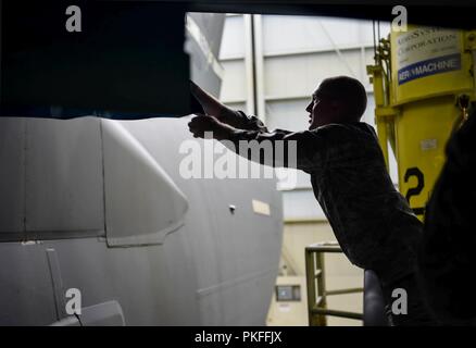 Il personale Sgt. Cody Lange, il sessantesimo di manutenzione aeromobili squadrone manutenzione strutturale e tecnico, rimuove il rivestimento di plastica di una sezione di un C-17 Globemaster III da Travis Air Force Base in California, che era stato messo lì per proteggerla mentre la C-17 fu dipinto il 6 agosto 2018, a base comune Lewis-Mccorda, nello Stato di Washington Le leggi della California evitare Travis aviatori di verniciatura a spruzzo loro C-17s, in modo che lo ha portato al McChord dove è consentito. Foto Stock