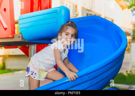 Ritratto di carino bambina holding e cursori di arrampicata per raggiungere il top sul parco giochi Foto Stock