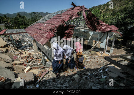 Pemenang, West Nusa Tenggara, Indonesia. Xiv Sep, 2018. Gli studenti a piedi vicino dalla sua scuola è crollato il loro in Pemenang, West Nusa Tenggara a Settembre 13, 2018 dopo una serie di terremoti su agosto 5. Indonesiano di agenzie di aiuto e i funzionari si precipitò per aiutare i sopravvissuti dopo il terzo quake disastro in meno di un mese sulla isola di Lombok, dove alcuni 555 persone sono morte e circa 400 mila persone sono rimaste senza tetto o spostato dopo il forte terremoto che ha sconvolto il popolare isola turistica. Indonesia, una delle più soggette a disastri nazioni della terra si trova a cavallo della cosiddetta Pacific ''anello di fuoco'', Foto Stock