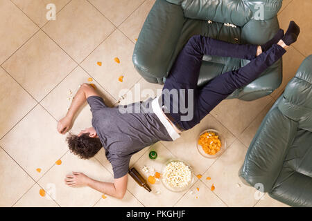 Giovane uomo dopo heavy partying a casa. Un sacco di birra e cibo spazzatura Foto Stock