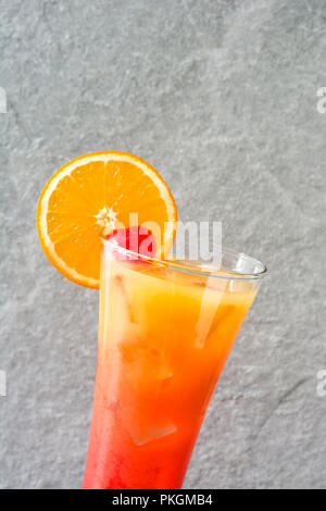 Tequila Sunrise cocktail in vetro su pietra grigia Foto Stock