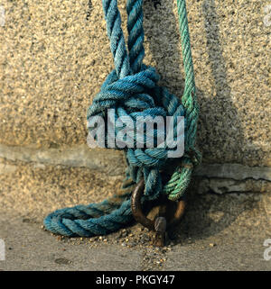 Primo piano di corde blu e verdi in un nodo su sfondo di pietra Foto Stock