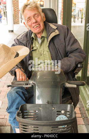 Vecchio Uomo disabili in una sedia elettrica in Canterbury High Street, Canterbury, nel Kent, Inghilterra, Regno Unito. Foto Stock