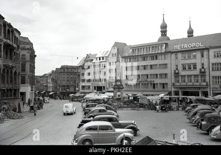 Anni '1950, storia, dopoguerra, Centro città, Colonia, Germania, scena di strada che mostra edifici e automobili dell'epoca nella piazza acciottolata della città con bancarelle all'aperto. Vecchie linee di tram viste nell'immagine. Foto Stock