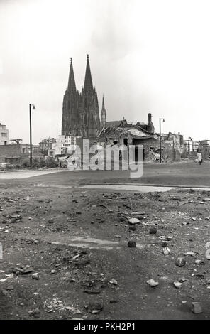 Anni '50, storico, Koln, Germania, un sito di bomba e rovinati edifici che mostrano i danni rimasti dopo la seconda guerra mondiale. La famosa cattedrale gotica della città, che non è stata distrutta nonostante i bombardamenti, è visibile sullo sfondo. Foto Stock