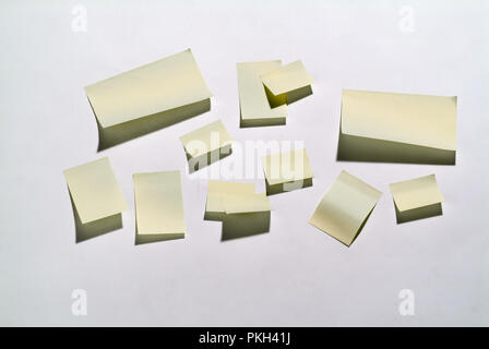 Giallo note di carta inceppata sul muro con ombra. Foto Stock