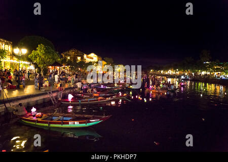 Hoi An di notte con i turisti in barca sul fiume della tradizionale e storica città. Di notte le lanterne sono accese, Foto Stock