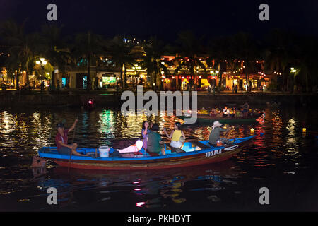 Hoi An di notte con i turisti in barca sul fiume della tradizionale e storica città. Di notte le lanterne sono accese, Foto Stock