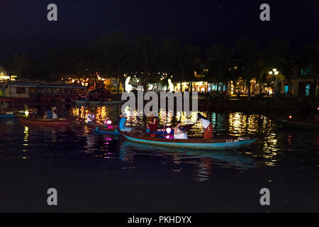 Hoi An di notte con i turisti in barca sul fiume della tradizionale e storica città. Di notte le lanterne sono accese, Foto Stock