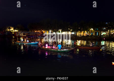 Hoi An di notte con i turisti in barca sul fiume della tradizionale e storica città. Di notte le lanterne sono accese, Foto Stock