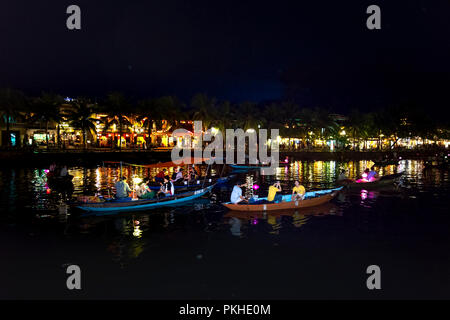 Hoi An di notte con i turisti in barca sul fiume della tradizionale e storica città. Di notte le lanterne sono accese, Foto Stock