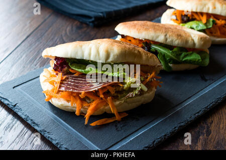 Taiwan ha Pane Pita Bun panino Gua Bao con pancetta affumicata, fette di carota e verde dall'Asia. Pastirma / pastrami sandwich Foto Stock