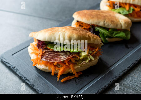 Taiwan ha Pane Pita Bun panino Gua Bao con pancetta affumicata, fette di carota e verde dall'Asia. Tradizionale cibo organico. Foto Stock