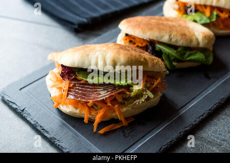 Taiwan ha Pane Pita Bun panino Gua Bao con pancetta affumicata, fette di carota e verde dall'Asia. / Pastrami sandwich pastirma Foto Stock