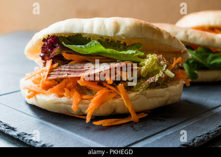 Taiwan ha Pane Pita Bun panino Gua Bao con pancetta affumicata, fette di carota e verde dall'Asia. Pastrami / pastirma Foto Stock