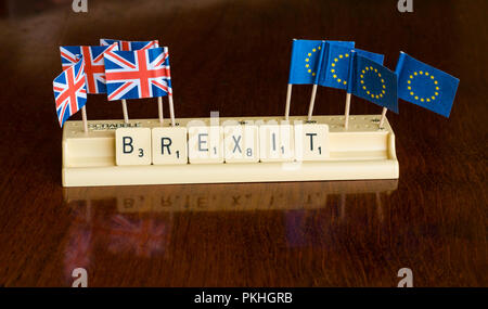 Lettere di Scrabble Brexit ortografia nel vassoio di Scrabble con Union Jack e bandiera UE su mogano scuro dello sfondo Foto Stock