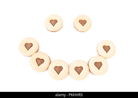 Una faccina sorridente fatta di cioccolato e biscotti a forma di cuore i cookie. Foto Stock