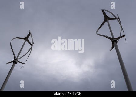 Asse verticale di generazione di energia eolica mulini con scuri nuvoloso nubi nel cielo che mostra futuro incerto di fonti di energia verde Foto Stock