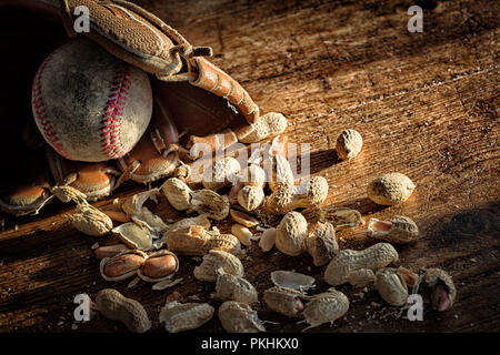 Il baseball, il guanto e la vecchia sfera sul legno rustico con arachidi sparsi e conchiglie. Tema per l'America sport preferito. Vintage look and feel. Copia dello spazio. Foto Stock