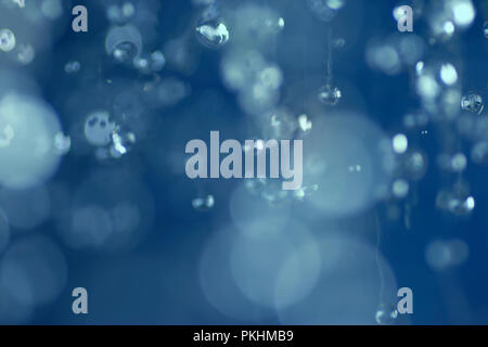 La caduta di gocce d'acqua. La levitazione delle gocce di pioggia. Abstract blue bokeh sfondo sfocato. Foto Stock