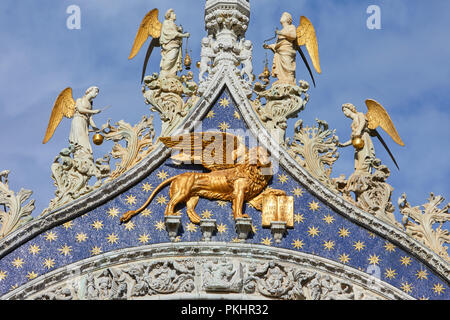 San Marco golden leone alato statua con angeli sulla basilica facciata, simbolo di Venezia in una giornata di sole in Italia Foto Stock