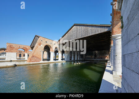 Arsenale veneziano con dock, ampia canal e arcade in una giornata di sole a Venezia, Italia Foto Stock