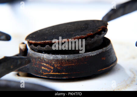 Una ruggine nero bruciatore di gas su bianco fornello per riscaldare il cibo per mangiare. Molto vecchia macchina Foto Stock