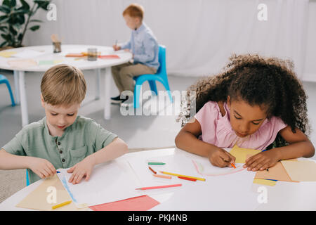 I bambini in età prescolare multiculturale foto di Disegno con matite in aula Foto Stock