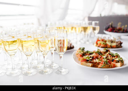 Lotto di bicchieri di champagne o vino sul tavolo nel ristorante. tavolo da buffet con un sacco di deliziosi spuntini. Foto Stock