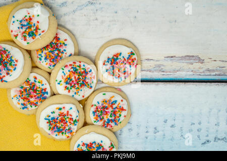 Carino delizioso zucchero vanigliato cookie disposti su un blu sullo sfondo di legno. Spruzza sulla vaniglia frosted cookie. Tovagliolo giallo Foto Stock