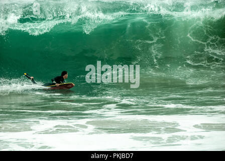 Bodyboarder vola sotto il labbro di una grande onda al cuneo sulla Isola Balboa di Newport Beach in California. (USA) Foto Stock