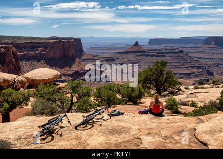 Una donna si ferma per una pausa mentre in sella ad una mountain bike lungo un sentiero in Dead Horse Point State Park, Utah, Stati Uniti d'America. Foto Stock