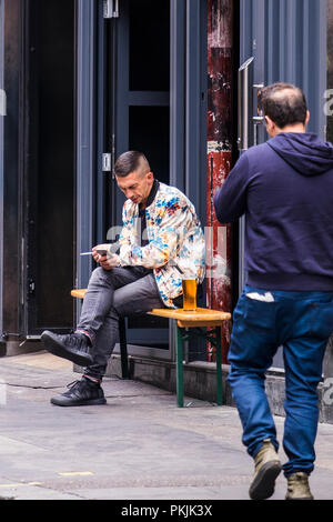 Persone che utilizzano dispositivi mobili fuori strada, City of Westminster, Londra, Inghilterra, Regno Unito Foto Stock