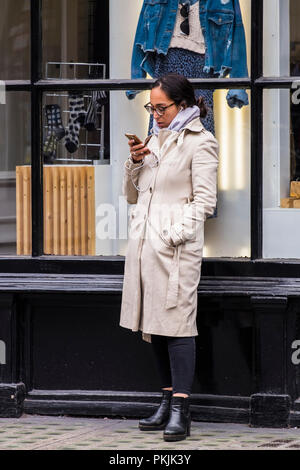 Persone che utilizzano dispositivi mobili fuori strada, City of Westminster, Londra, Inghilterra, Regno Unito Foto Stock