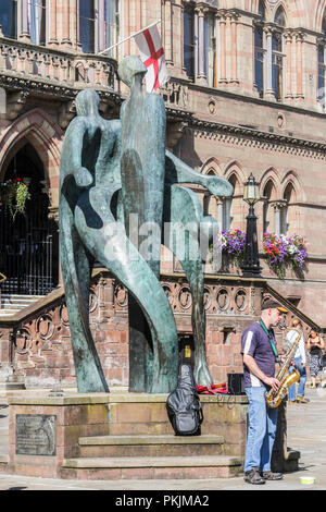 Chester, Inghilterra - 16 agosto 2016: un suonatore ambulante svolge un sassofono dalla statua al di fuori del Municipio. La statua è da Stephen Broadbent. Foto Stock