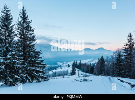 Sunrise mattina inverno villaggio montano di periferia in nero Cheremosh river valley tra alp. Vista dalla campagna coperta di neve percorso sul versante collinare con chr Foto Stock