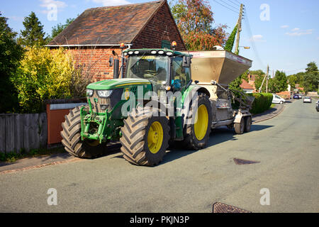 John Deere 6155R il trattore e il rimorchio parcheggiato nella strada principale al Gnosall Foto Stock