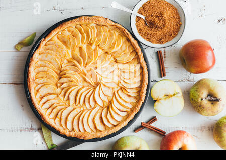 Pane appena sfornato la torta di mele crostata con crema pasticcera ripieno su un rustico in legno bianco sullo sfondo. Vista superiore Foto Stock