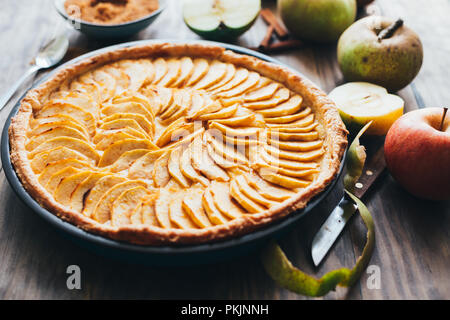 Pane appena sfornato la torta di mele crostata con crema pasticcera ripieno su una tavola in legno rustico Foto Stock