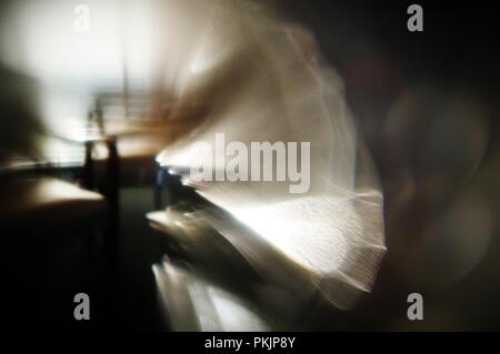 Abstract di una sedia antica con la tenda a veneziana ombre attraverso di esso shot attraverso un vetro. Foto Stock