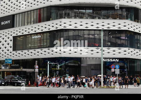 Le persone in attesa in un crosswalk in Ginza di fronte al moderno luogo di Ginza edificio che ospita la Nissan showroom di attraversamento. Foto Stock