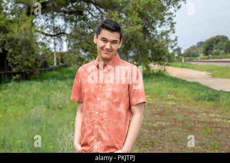 A 22 year old man standing all aperto con le mani in tasca a Carlsbad, California Foto Stock