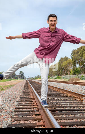 Giovane uomo in equilibrio su traclks ferroviaria in Calsbad, California Foto Stock